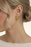 Gold filigree hoop earrings worn on ear, small floral hoops with vintage-inspired detail