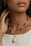 Close-up on model wearing crystal star and baroque pearl drop necklace with amethyst beads