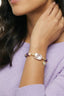 Model wearing gold plated bracelet with baroque pearl, amethyst beads and star charm outdoors by the sea