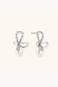 Pair of rhodium-plated sterling silver bow stud earrings with baguette crystals and freshwater pearl drops.