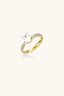Gold plated oval zirconia solitaire ring with pavé band on neutral background