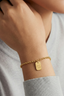 Woman wearing gold bracelet with engraved good luck pendant
