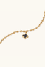 Close-up of mother-of-pearl quatrefoil charm on gold-plated beaded bracelet