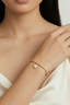 Model wearing Clover Pearl Charm Bracelet gold beaded clover bracelet on wrist