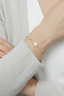 Model wearing mother-of-pearl butterfly bracelet with crystal accents on wrist in soft gold finish